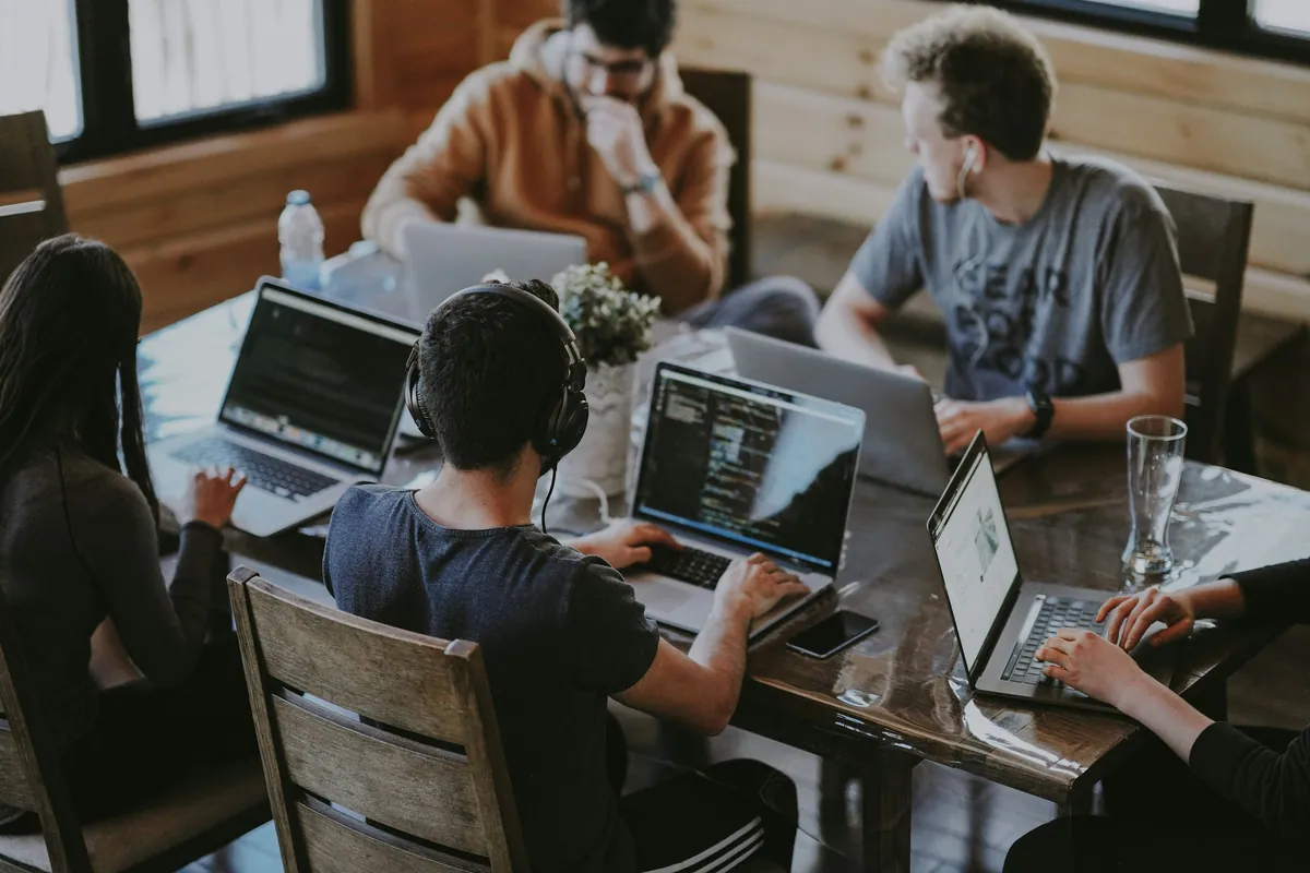 Gruppe arbeitet gemeinsam an Laptops an einem Tisch